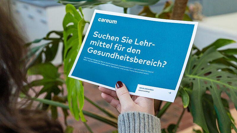 Eine Frau sieht sich ein Mailing für Careum an